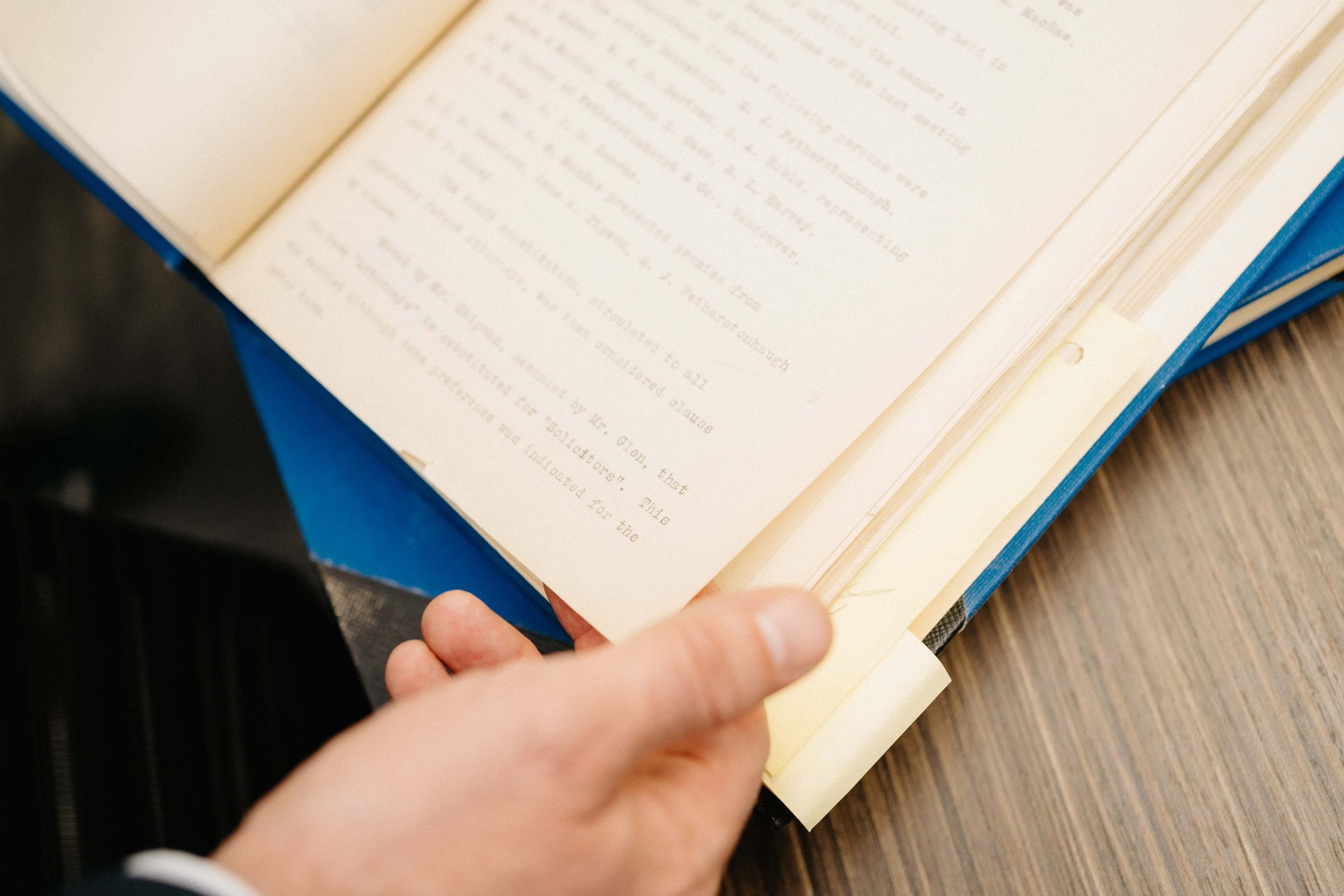 Gros plan d'une main tenant un livre ouvert aux pages jaunies.